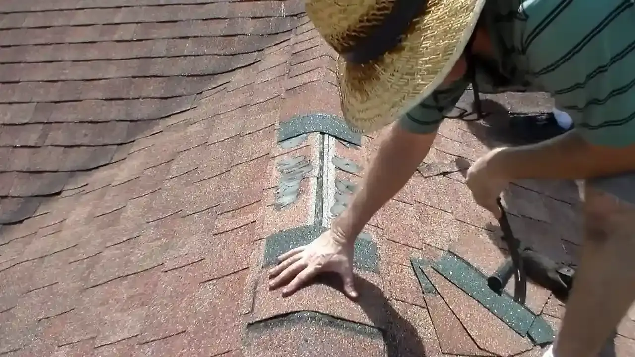 Roofer fastening replacement asphalt shingles during a residential roof repair.