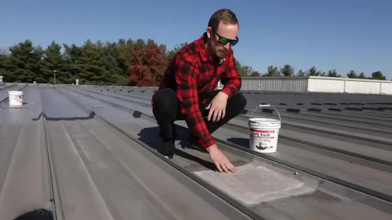 Roofing contractor patching a damaged section of a commercial metal roof eugene.