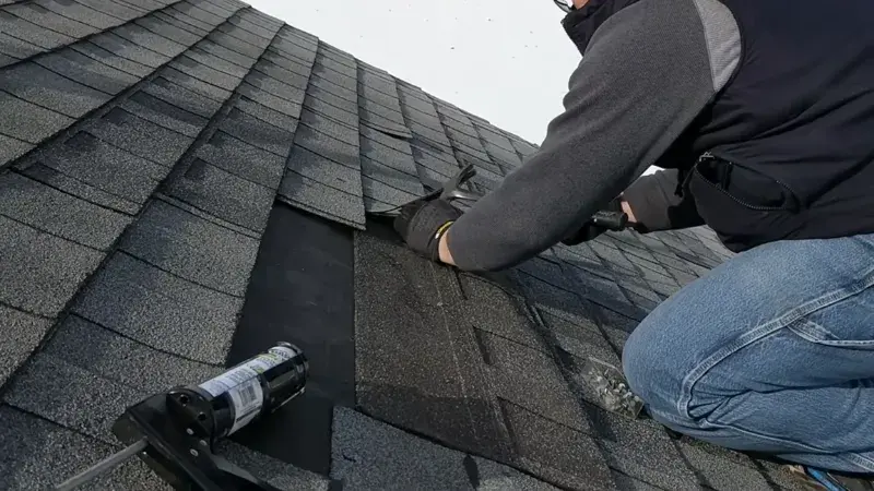 Roofing contractor repairing damaged asphalt shingles on a residential roof in Anaheim, California.